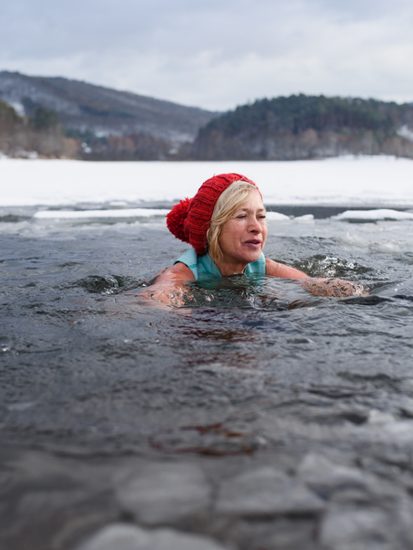 Front view of a woman swimming in icy water in dramatic landscape